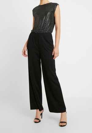 Pantalones anchos negros combinados con un top sin mangas adornado con lentejuelas negras brillantes. Textura suave con una cintura ceñida.