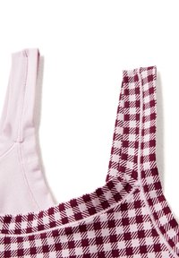 Canotta di cotone con una base rosa chiaro; una spallina presenta un motivo a quadretti bordeaux e bianco. Texture liscia con cuciture sicure.