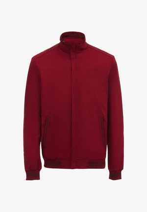 Jachetă roșie cu guler înalt, două buzunare laterale, manșete cu nervuri și o textură netedă. Prezintă un design minimalist și fără închizători vizibile.