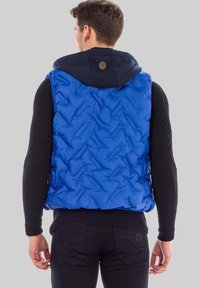Blauer Steppweste mit quilteter Textur, kapuzenförmigem Design in Marine, gerippte schwarze Ärmel. Mit einem runden Logo am hinteren Halsbereich.