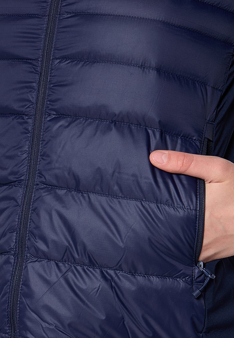 Gilet isolant bleu marine avec un motif matelassé, fermeture éclair et poche latérale. Tissu lisse et léger avec peu de coutures visibles.