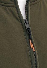 Olive green zip-up jacket with a smooth texture, featuring a black zipper and brown accent pull, designed for a fitted look.