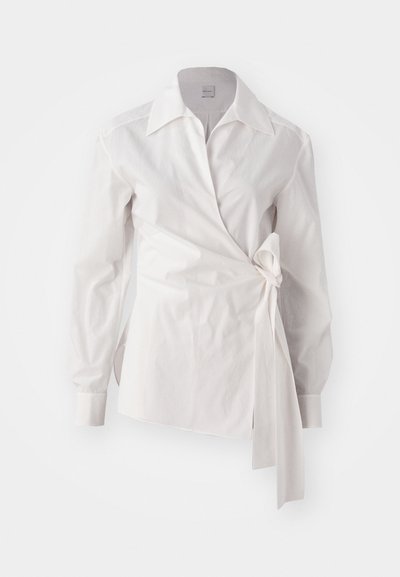 White long-sleeve wrap blouse with a classic collar and a side knot detail on a plain background.