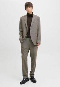 Men's gray suit jacket paired with matching trousers, featuring a subtle check pattern, worn over a brown turtleneck and black shoes.