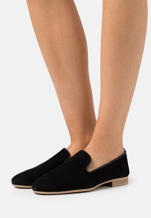 Sorte ruskinds slip-on sko med rund tå, minimal syning og en lille hæl. Har glatte kanter og en naturlig trædetalje på hælen.