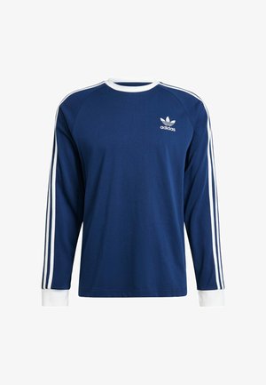 Langere mouwen blauwe shirt met witte accenten, met een ronde hals, witte manchetten en drie witte strepen op elke schouder. Adidas-logo op de borst.
