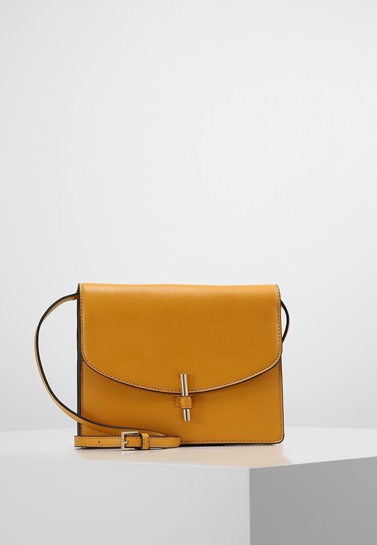 Borsa a tracolla in pelle gialla con chiusura a pattina, dotata di una sottile tracolla regolabile e dettagli in metallo argentato, design minimalista con linee pulite.