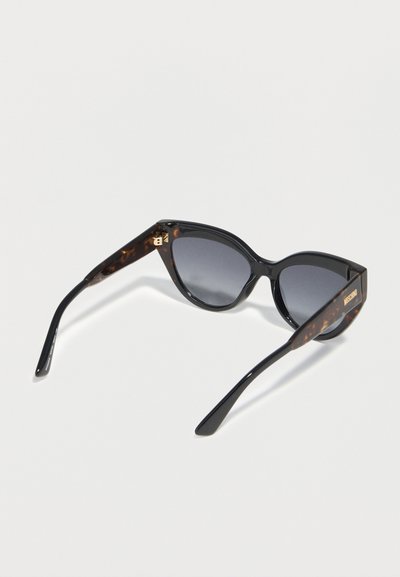 Μαύρα γυαλιά ηλίου με σχήμα γάτας και βραχίονες σε σχέδιο χελώνας, με σκουρόχρωμους φακούς και το λογότυπο Moschino στους πλευρικούς βραχίονες.