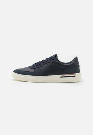 Sneaker in pelle blu con finitura liscia, punta rotonda e suola in gomma bianca. Presenta accenti a contrasto marroni e neri sul tallone.