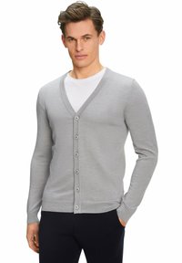Cardigan grigio a maglia con scollo a V, maniche lunghe e chiusura con bottoni. Finitura testurizzata con un design aderente, abbinato a una t-shirt bianca.