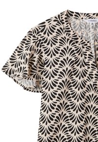 Blusa a maniche corte nera e crema con motivo a foglie, che presenta un collo rotondo e dettagli di cucitura sottili.