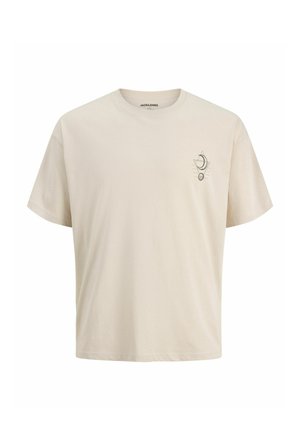 Dreng står og smiler iført en sort hættetrøje med lynlås, beige t-shirt, løse sorte bukser, beige sko og en mørkegrå baseballkasket.