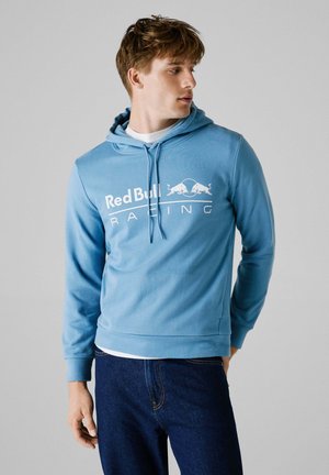 Light blue hoodie made of soft fabric with a front kangaroo pocket. Features a white "Red Bull Racing" logo across the chest.