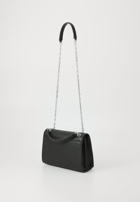 Sac à main en cuir noir avec une forme structurée, doté d'une bandoulière en chaîne amovible et d'une anse incurvée. Texture lisse et accents en métal argenté.