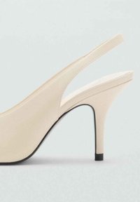 Scarpa con tacco alto beige, con finitura liscia, punta affusolata e un accento sul tacco nero. Presenta un design elegante e minimalista.