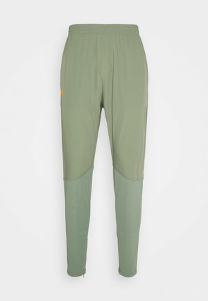 Lichtgroene taps toelopende sportbroek met elastische tailleband en donkerdere groene panelen op de onderbenen.