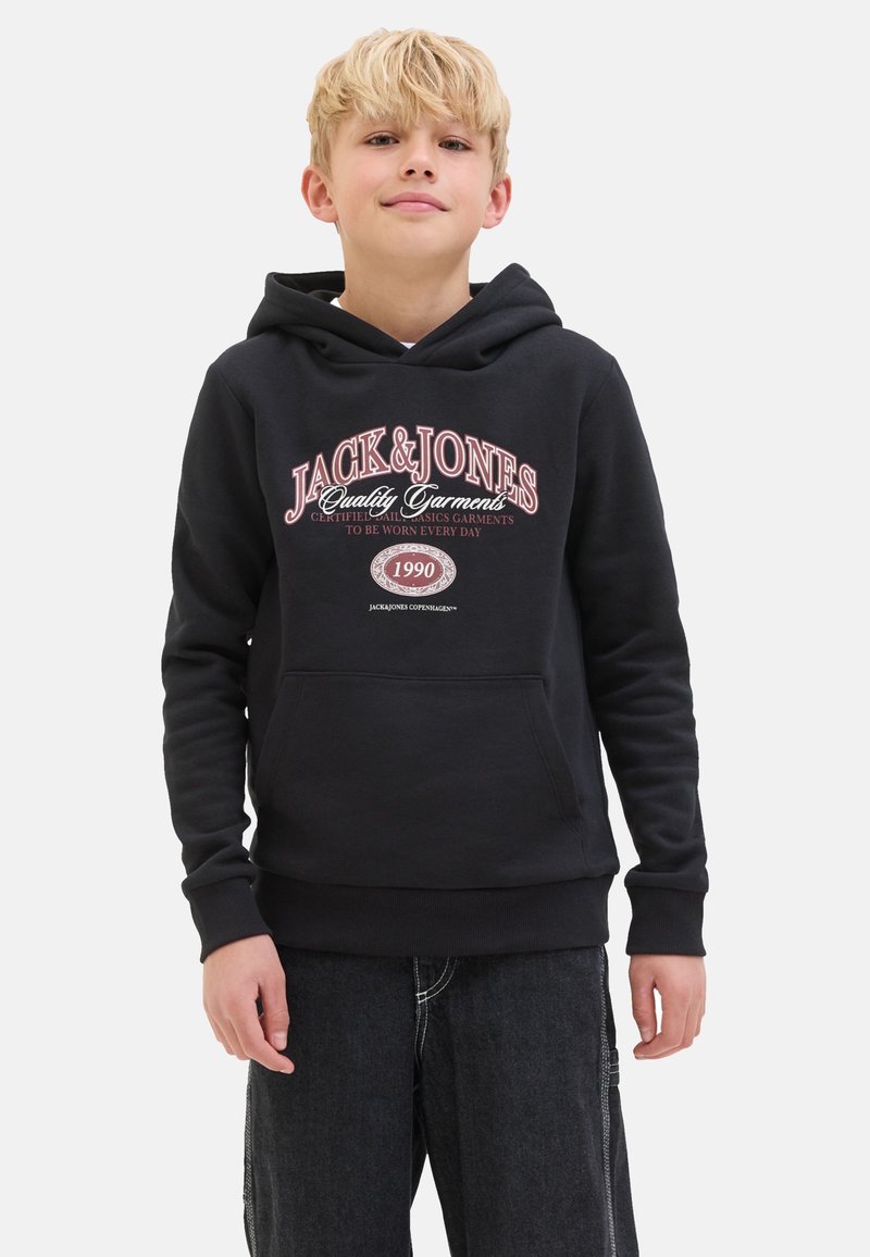 Hoodie noir avec une poche kangourou à l'avant, des poignets et un ourlet côtelés, avec des graphismes textuels rouges et blancs. Porté avec un short en denim foncé.