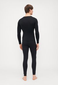 Mustvalge pika varrukaga topp ja sobivad leggingid, mis on valmistatud venivast kangast. Sile tekstuur ilma nähtavate mustriteta, mugavatega paeltega pahkluude juures.