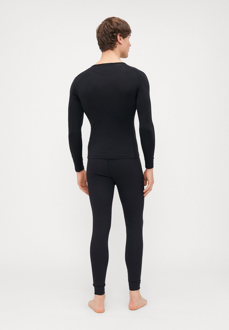 Black long-sleeve top and fitted leggings made from stretch fabric. Smooth texture with no visible patterns, featuring snug cuffs at ankles.