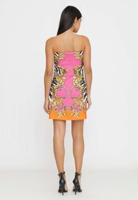 Abito colorato con una parte anteriore rosa, lati a motivo zebra, dettagli dorati e un orlo arancione, sostenuto da spalline sottili. Tacchi alti neri.