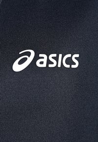 Musta urheilukangas, jossa on poimuttunut rakenne ja näkyvä valkoinen "asics"-logo. Ei muita kuvioita tai yksityiskohtia.