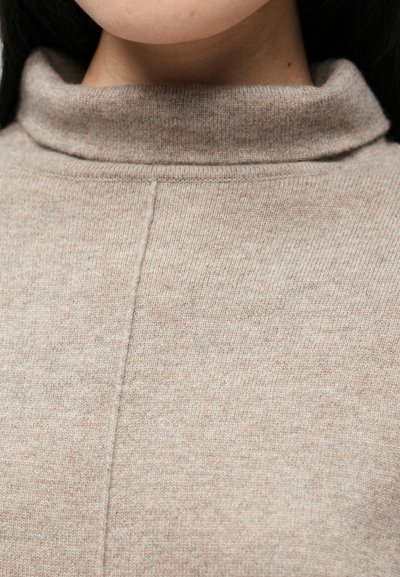 Κρεμ πουλόβερ με ζιβάγκο σε ανοιχτή μπεζ απόχρωση, κατασκευασμένο από μαλακό, υφασμένο ύφασμα. Διαθέτει ψηλό γιακά και κεντρική ραφή στο μπροστινό μέρος.
