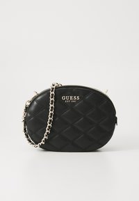 Borsa a spalla nera trapuntata in ecopelle, con tracolla a catena argentata e dettaglio del logo dorato sulla parte anteriore. Forma ovale con chiusura a zip.