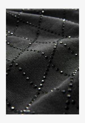 Tejido negro con una superficie texturizada, que presenta un patrón de cuadrícula adornado con pequeños y brillantes remaches negros espaciados uniformemente por toda la tela.