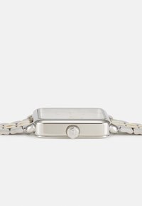 Montre rectangulaire en argent avec un cadran de couleur claire, une couronne texturée, et un bracelet à maillons comportant des éléments argentés et blancs alternés.