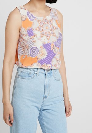 Top senza maniche in tessuto leggero con un motivo geometrico nei colori arancione, viola e crema. Abbinato a jeans azzurri a vita alta.