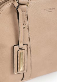 Borsa a tracolla in pelle beige con finiture dorate, caratterizzata da una superficie testurizzata, dettaglio del logo e chiusura con zip superiore.