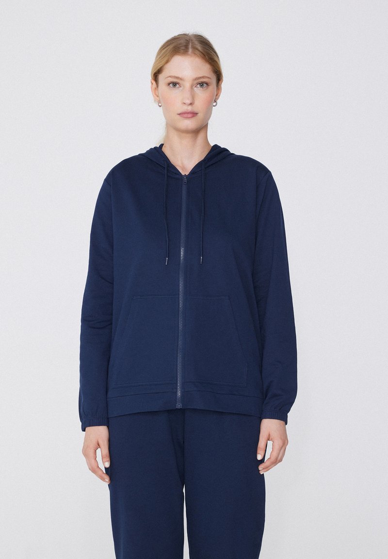Sudadera con cremallera de color navy, hecha de una tela suave, con capucha, bolsillos frontales y puños de canalé para un ajuste cómodo.