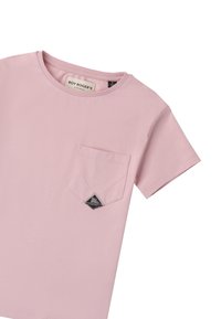 Camiseta de manga corta color rosa claro, con cuello redondo, que presenta un bolsillo delantero con una etiqueta negra. Fabricada en suave tejido de algodón.