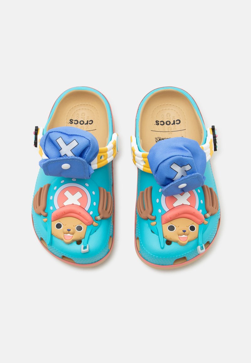 Παιδικά τιρκουάζ Crocs με χαρακτήρα καρτούν με κόκκινο καπέλο και κέρατα στην κορυφή, με προσαρτημένα μπλε γοητευτικά καπέλα με λευκά σύμβολα Χ.