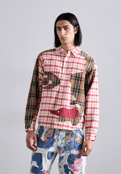 Chemise boutonnée avec un design en patchwork, combinant des motifs à carreaux rouges et blancs avec des accents de plaid marron et des motifs faciaux abstraits.