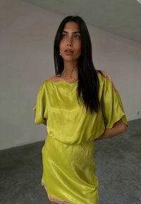 Vestido de cetim verde-lima com mangas soltas e renda ao longo do decote e da barra, apresentando um corte descontraído e uma textura suave.
