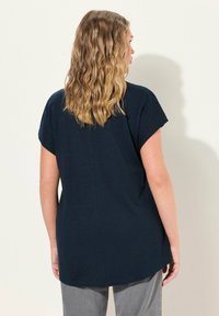 Tmavě modré tričko s krátkým rukávem a kulatým výstřihem, volnější střih, rovný šev na zadní straně, vyrobené z měkké, lehké tkaniny.