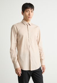 Hellbeige Langarmhemd mit einem dezenten Muster, Button-Down-Kragen und Manschetten, aus einem glatten, leichten Stoff gefertigt.