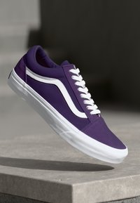 Purple canvas sneaker with white accents, flat laces, and a distinctive side stripe design. Rubber sole and rounded toe.