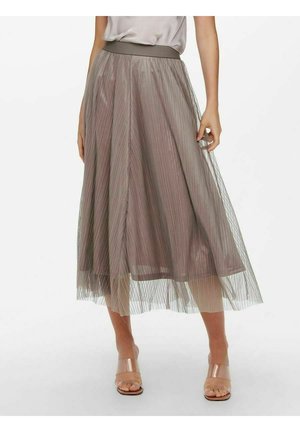 Kvinde iført en taupe plisseret midi nederdel med transparent overlay og nøgen åbent tå blokhæls sandal på hvid baggrund.