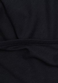 Tissu noir avec coutures visibles et plis doux, montrant la texture et le motif de tissage en détail rapproché.