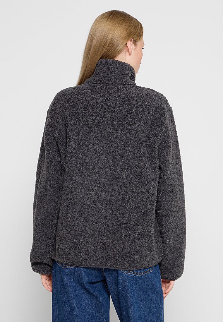Graue Fleecejacke mit hohem Kragen, lockerer Passform und strukturierten Oberflächen. Der Stoff ist weich und warm, ideal für legere Kleidung.