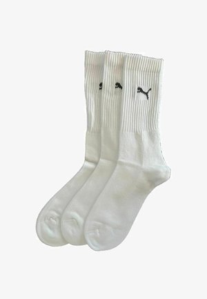Drei Paare weißer Crew-Socken mit gerippten Bündchen und schwarzem Puma-Logo auf jedem Bündchen, übereinander angeordnet vor einem weißen Hintergrund.