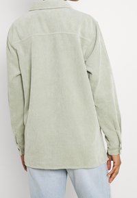 Ljusgrön kordoverkskjorta med en avslappnad passform, som har långa ärmar, krage och knappade ärmslut. Texturerade vertikala ränder.