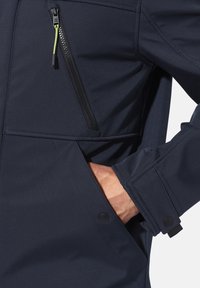Navy softshell jacket featuring a zippered chest pocket, adjustable cuffs, and a smooth texture with stitching details.