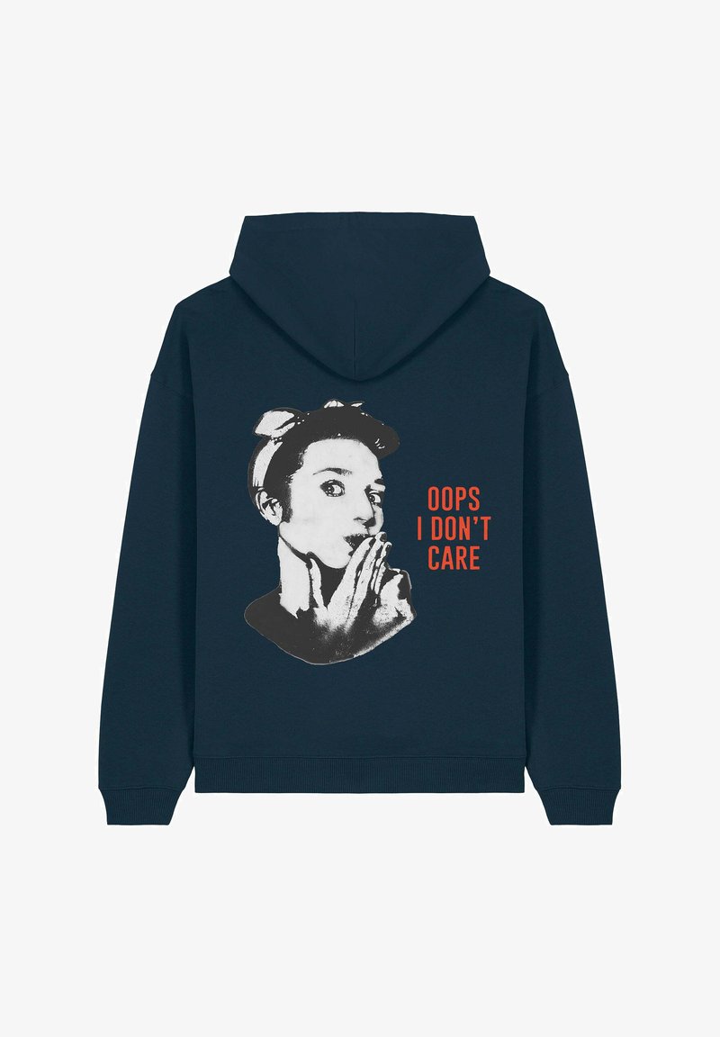 Mornarica dukserica s grafičkim uzorkom žene koja drži prst na usnama. Tekst glasi "OOPS I DON'T CARE" u narančastoj boji. Rebrasti manžeti i donji rub.