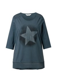 Mørk teal T-shirt med trekvartærmer, pyntet med en stjernegrafik, teksturerede skulderdetaljer og et vævet element ved kanten.
