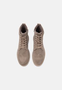 Ruske suede ankle bootsit pyöreillä varpailla, beigeillä nauhoilla, sivuvetoketjulla ja pehmeällä sisäpinnalla. Ompeleet beigeillä yksityiskohdilla kengänpohjien ympäri.