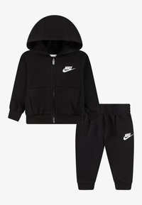 Tuta nera composta da due pezzi con felpa con cappuccio e zip frontale con tasca anteriore e pantaloni abbinati con vita elastica, entrambi con dettagli di logo bianchi.