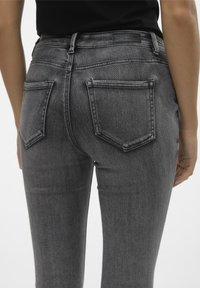 Grå denimjeans med en figurnära design, med bakfickor och subtila sömdetaljer. Slät textur och hög midja.